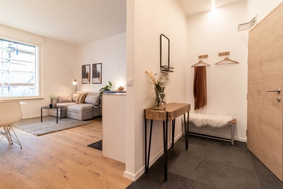 Heller Eingangs- und Wohnbereich mit Sofa, Teppich und harmonischem Licht