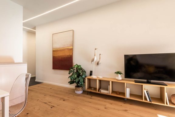 Moderner Wohnbereich mit TV-Board, Kunstbild und stimmiger Beleuchtung