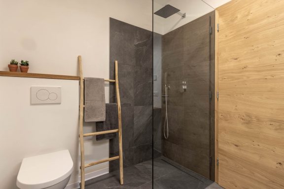 Badezimmer mit grauen Fliesen und bodenebener Dusche