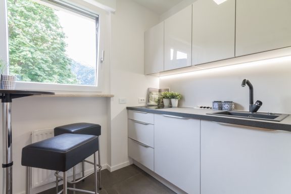 Sanierte Küche in Weiß mit Fensterlicht und strukturiertem Arbeitsbereich